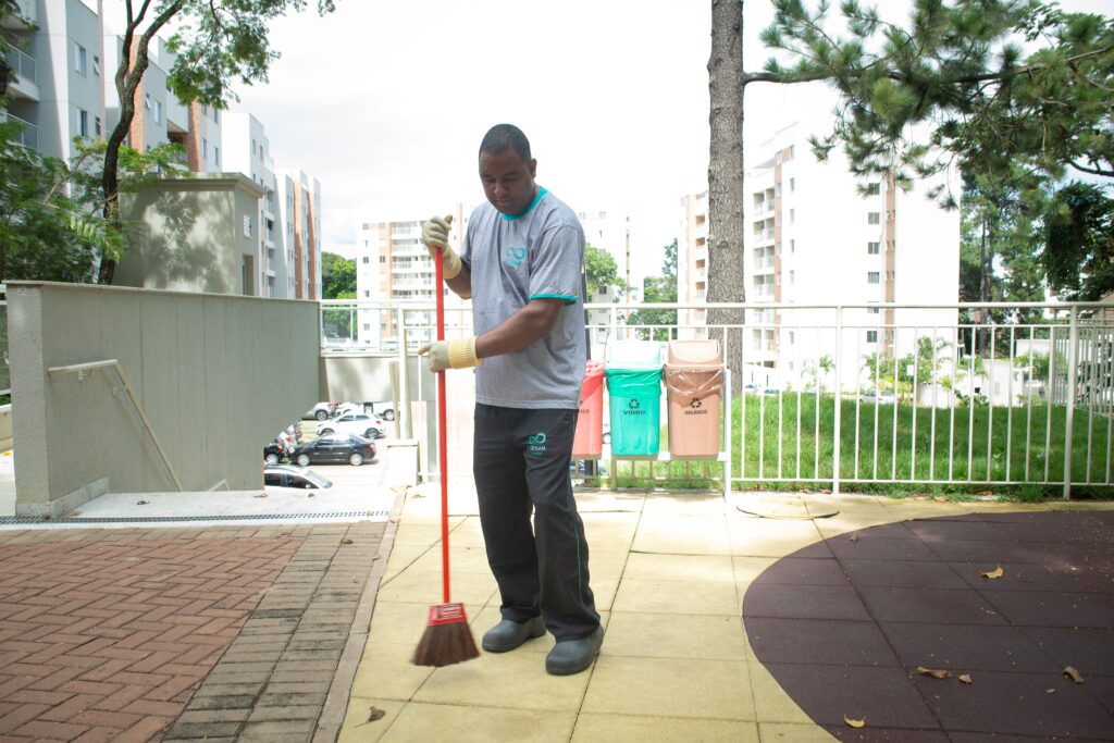 zelador de condomínio varrendo área externa em BH